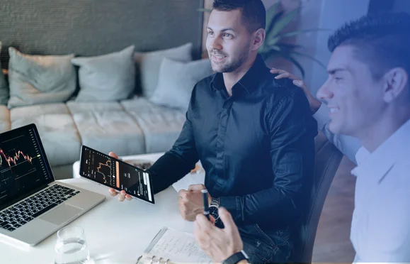 Professional analysing financial charts on tablet and laptop